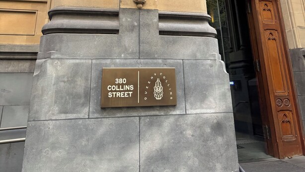 A building facade with ornate architectural details, including a lion statue, a plaque reading '380 Collins Street,' and a large arched entrance. - The Heritage Bank Apartment (Melbourne)