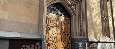 A building entrance with a large ornate gate, a sign for the ANZ Banking Museum, and a stone facade.