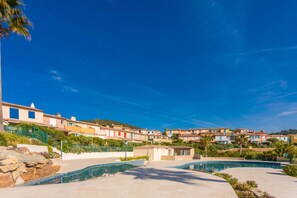 A pool area with a clear sky, a stone wall, and colorful buildings in the background. - Exceptional house with sea view and pool (Roquebrune-sur-Argens)