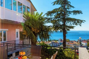A balcony with a view of the sea, a palm tree, and a building with a balcony. - Modern apartment with beautiful ocean views (Crikvenica)