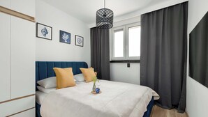 Ein Schlafzimmer mit Bett, Fenster und einer Pendelleuchte.