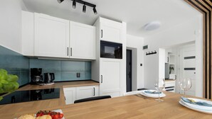 Eine moderne Küche mit weißen Schränken, einer schwarzen Arbeitsplatte und einem Holzespeisetisch, gedeckt mit Tellern und Gläsern.