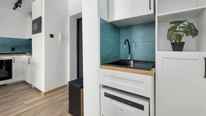 Eine moderne Küche mit weißen Schränken, einer türkisblauen Spritzschutzleiste, einem schwarzen Spülbecken und einer eingebauten Mikrowelle.