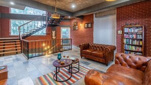 A spacious living area with a staircase, leather furniture, and a bookshelf. - ELIVAAS Fleur De Lis 4 BHK Villa (Kasauli)
