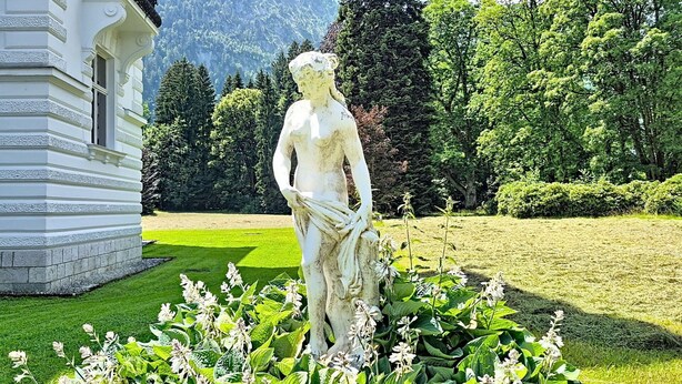 Una estàtua en un jardí amb un edifici al fons.