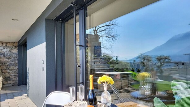 A balcony with a table set for a meal, a bottle of champagne, and a vase of flowers. - Lovely apartment for 2 people with WIFI, TV and panoramic view (Riazzino)