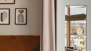 Ein Zimmer mit Blick auf einen belebten Platz, Wandkunst und eine hölzerne Bank.