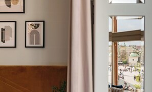 A room with a view of a public square, framed artwork on the wall, and a wooden bench. - Jana No. 2 Atelier Apartments — Kraków Old Town — by Luvaro (Kraków)