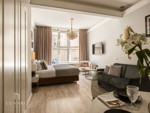 Una camera d'albergo moderna con un letto, un'area salotto e un tavolo da pranzo.