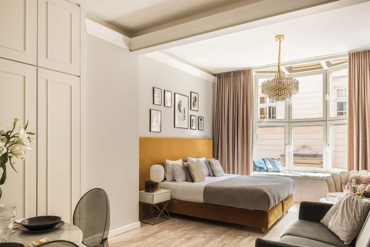 Ein Schlafzimmer mit Bett, Nachttisch, Lampe und einem Fenster mit Vorhängen.