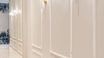 A hallway with white walls and gold fixtures, including wall sconces and a door with a gold handle.