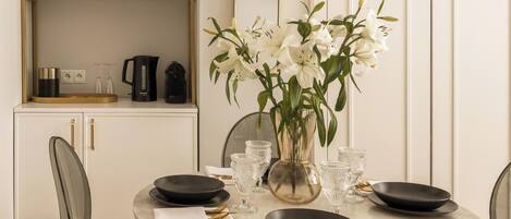 A dining table set with black plates, clear glassware, and a vase of white flowers.