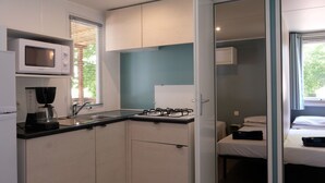 Una kitchenette compacta equipada con microondas, cafetera y cocina a gas.