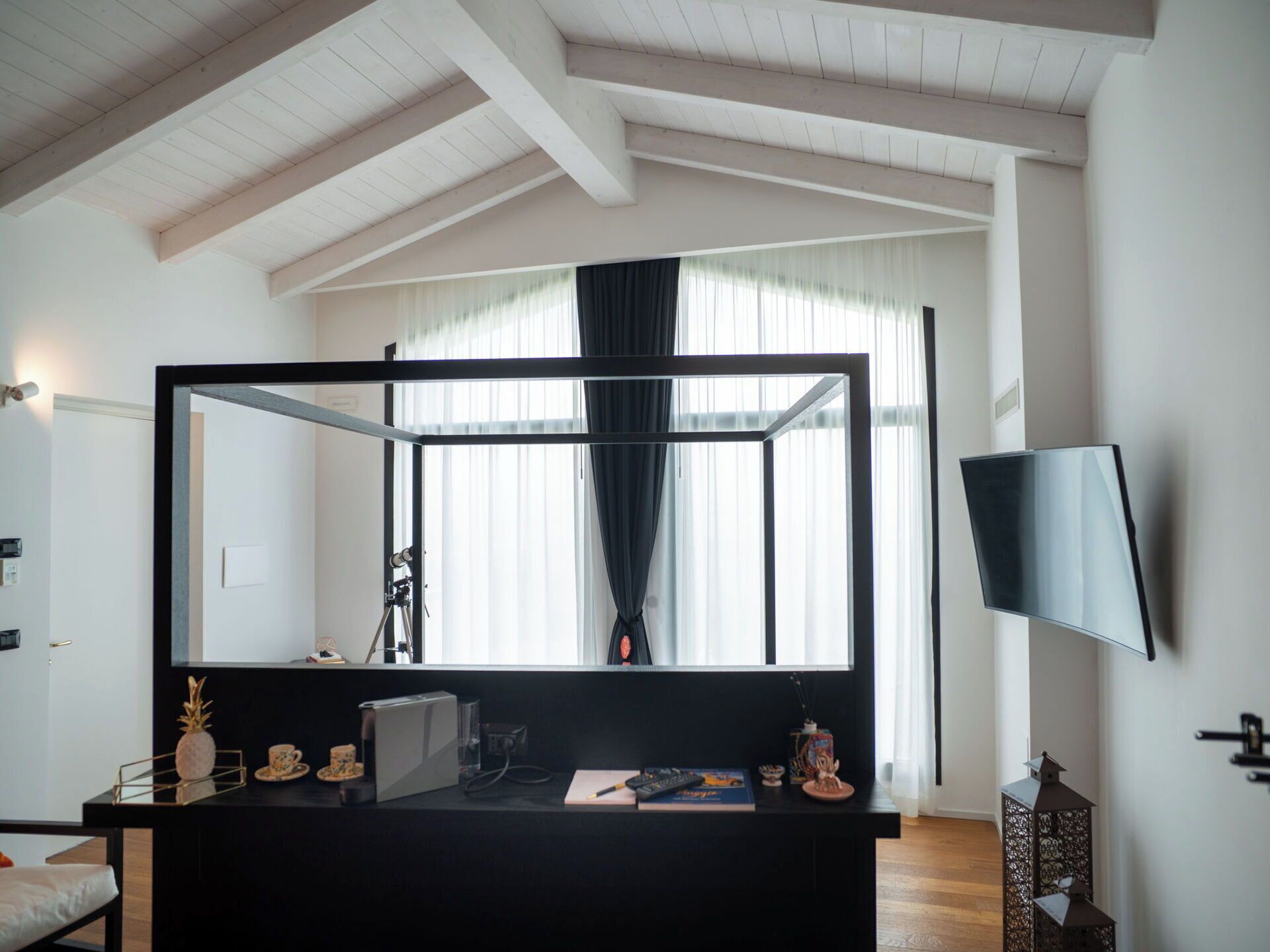Une chambre moderne dotée d’un grand miroir, d’un téléviseur à écran plat et d’un bureau sur lequel se trouvent divers objets.