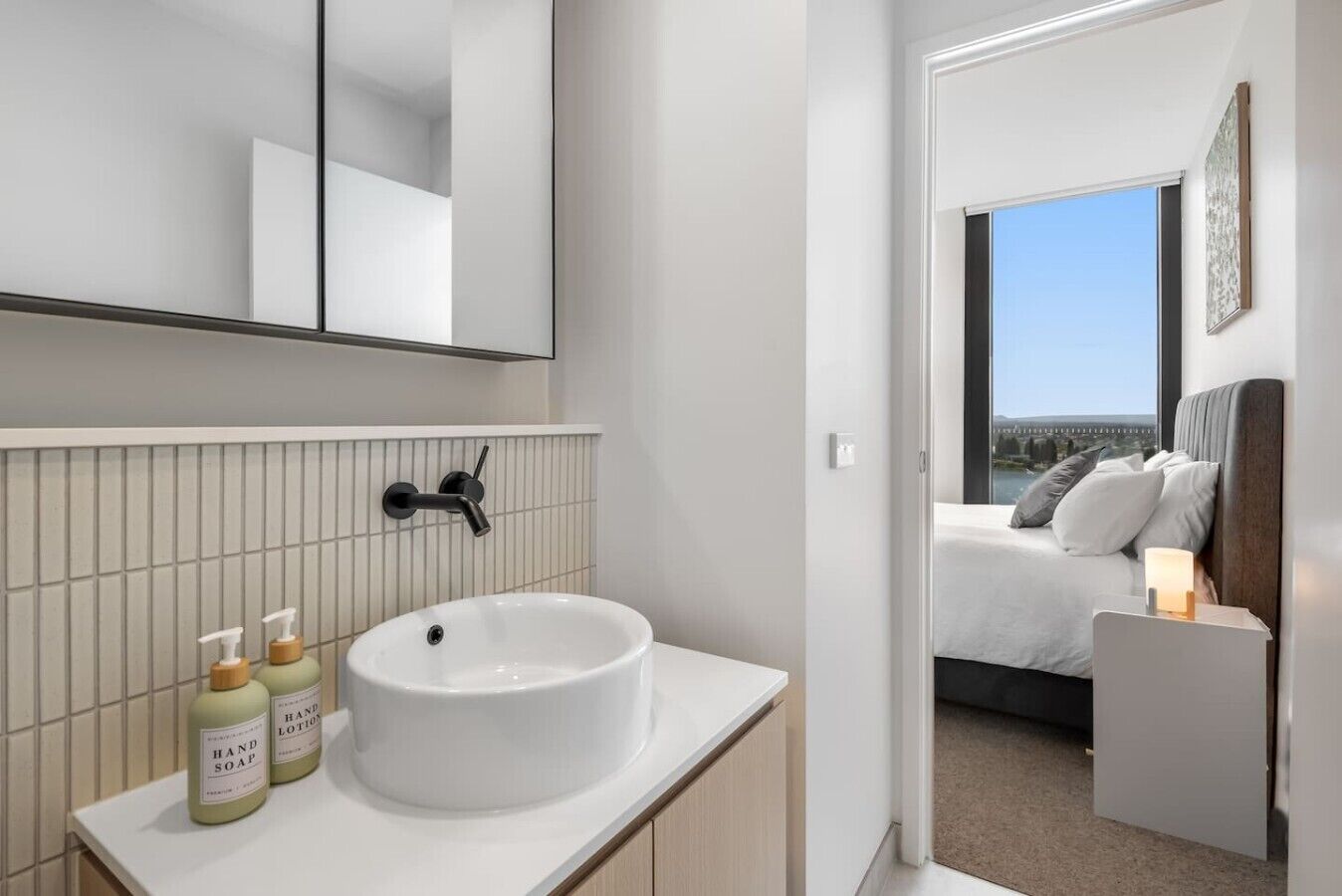A modern bathroom with a white sink, hand soap, and a mirror.