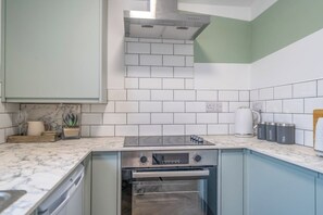A kitchen with white subway tiles, a stainless steel range hood, a built-in oven, and a marble countertop. - Gorgeous 3 Bed House Lancashire (Morecambe)