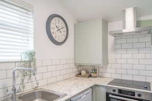 A kitchen with a sink, stove, oven, and a clock on the wall. - Gorgeous 3 Bed House Lancashire (Morecambe)