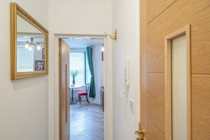 A hallway with a wooden door, a mirror, and a telephone. - Gorgeous 3 Bed House Lancashire (Morecambe)