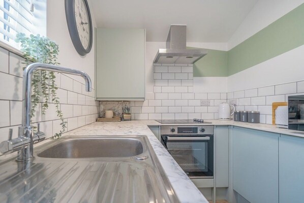 Una cocina con lavabo, estufa, horno y un reloj en la pared.