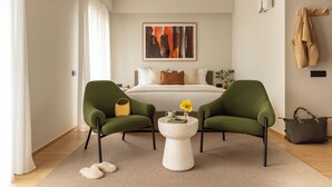 A modern bedroom with a bed, two green armchairs, a round coffee table, and a painting on the wall. - Bob W Milan Crocetta (Milan)