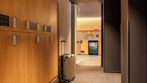 A hotel corridor with wooden walls, a luggage trolley, and a vending machine. - Bob W Milan Crocetta (Milan)