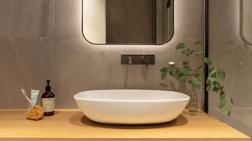 Ein modernes Badezimmer mit einem großen weißen Waschbecken, einem Spiegel und einer Holzauslage.