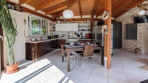 A modern kitchen with wooden beams, a dining table, chairs, and a large window.