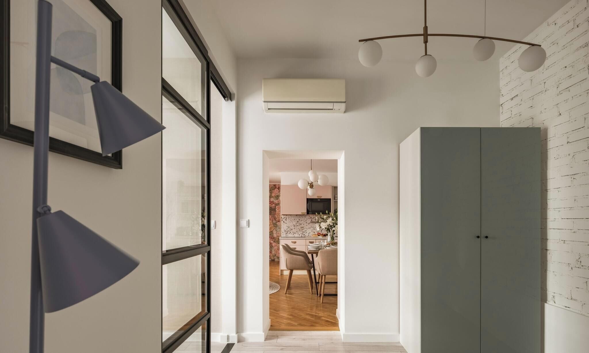 Un pasillo con una cocina moderna visible a través de una puerta abierta, que incluye un comedor con sillas y una mesa.