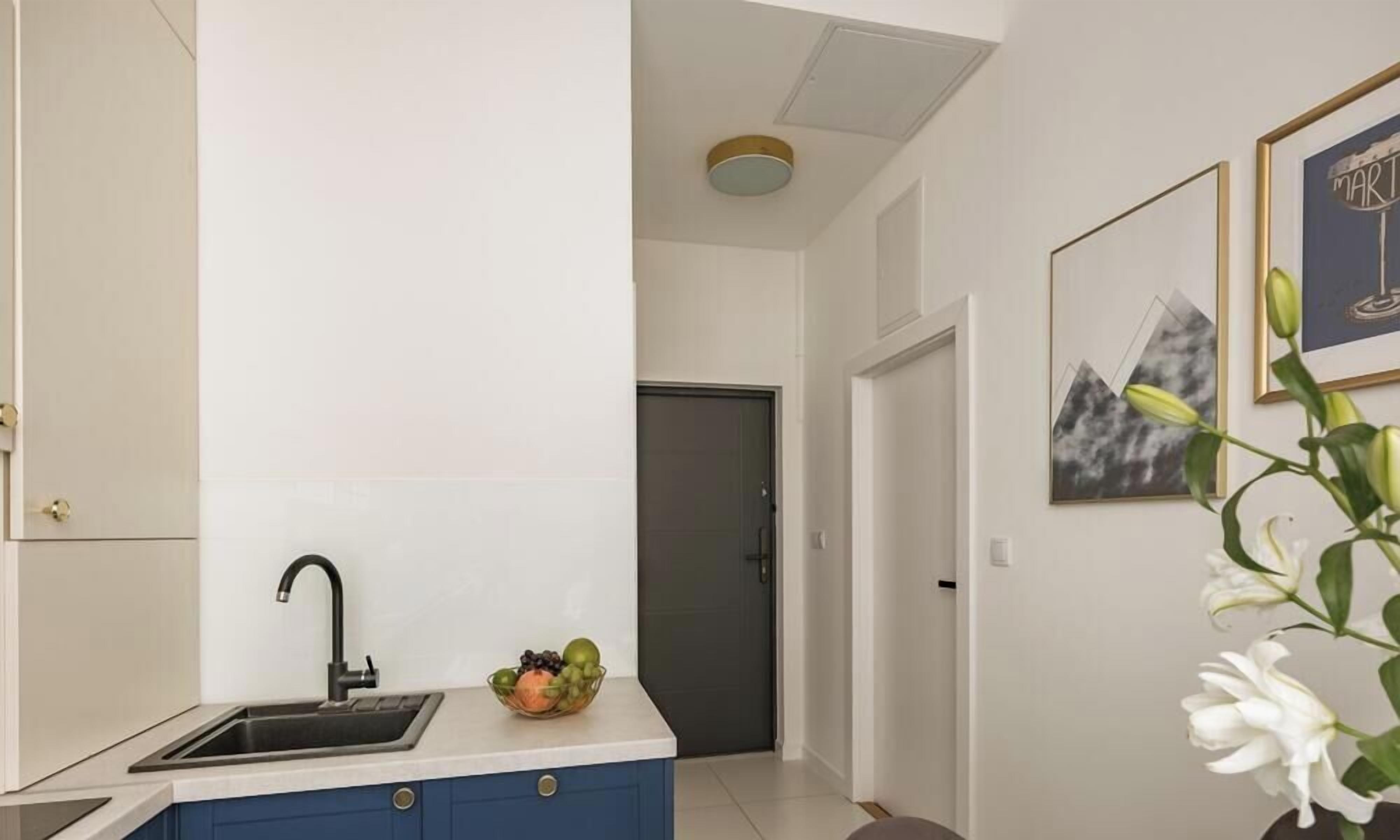 Una cocina moderna con un lavamanos, un tazón de fruta y una puerta al fondo.