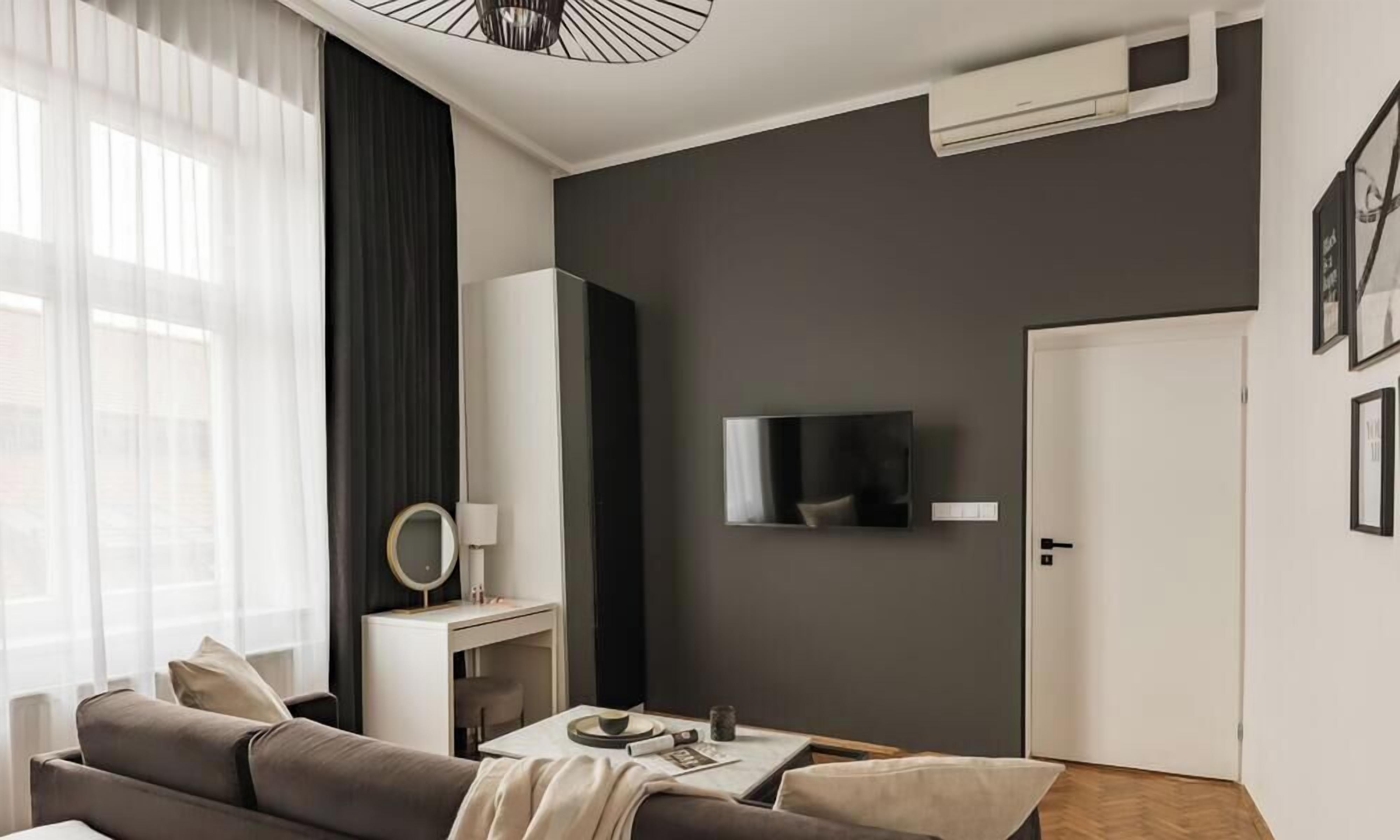 Una sala de estar moderna con un sofá, una mesita, un televisor montado en la pared y una puerta.