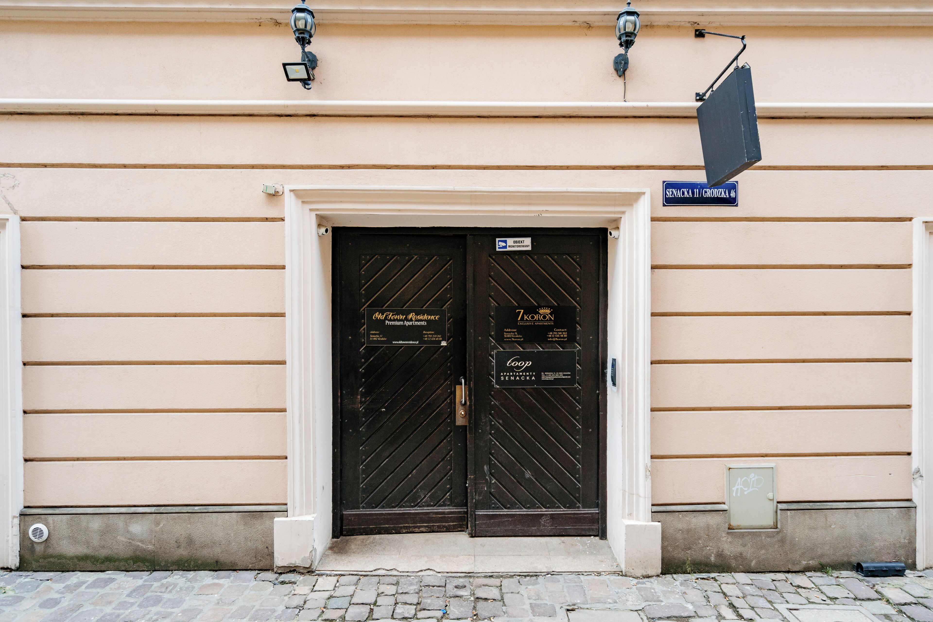 A building with two black doors, a sign above the doors, and a small window on the right side.