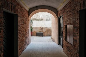 Un corridoio ad arco in mattoni, con una porta alla destra e una finestra alla sinistra.