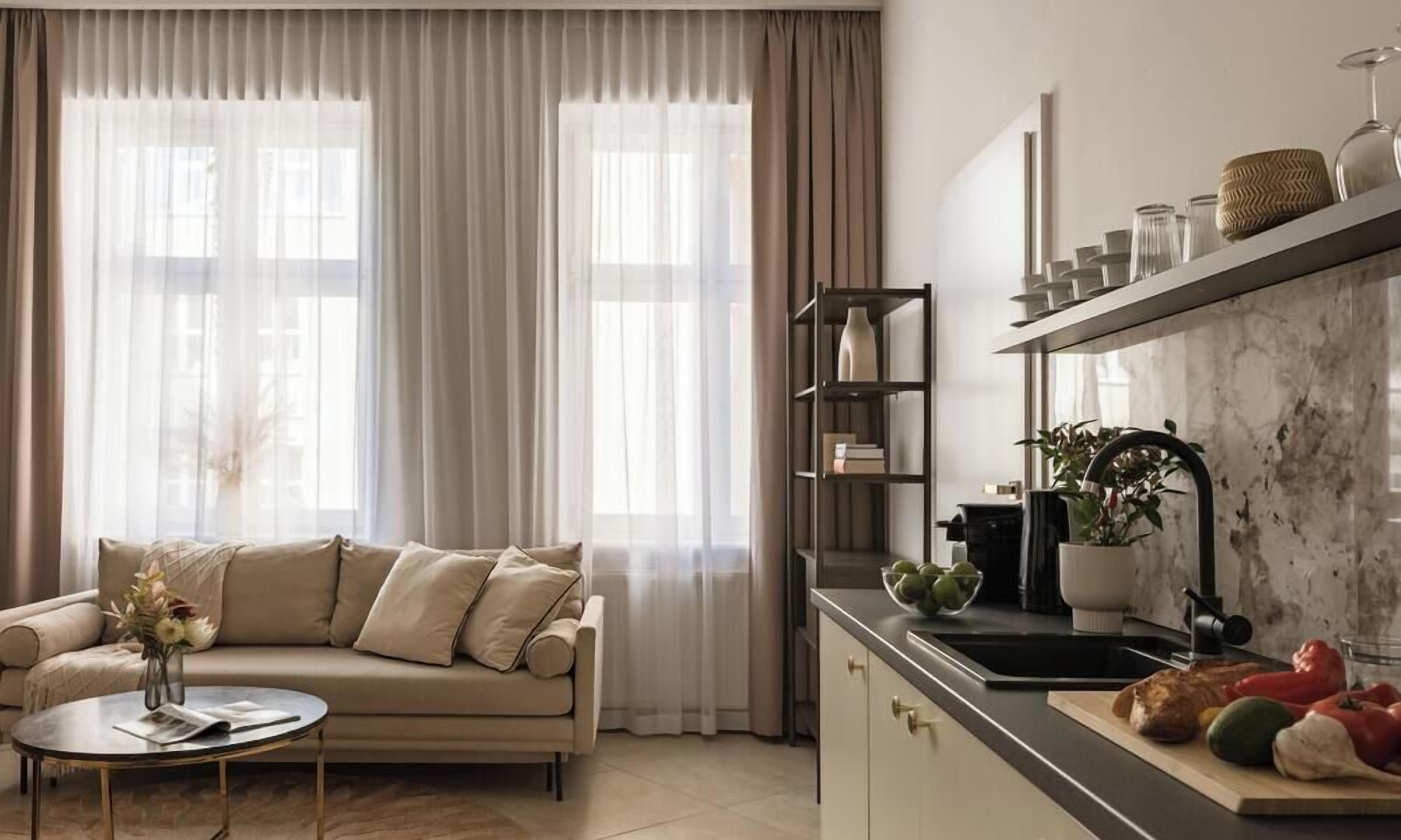 Una sala moderna con sofá, mesa de centro y una cocina con fregadero y encimera.