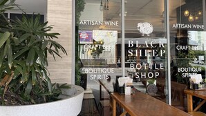 Liikkeen edessä on kyltit, joissa lukee ”ARTISAN WINE” ja ”CRAFT BEER”, sekä kyltit, joissa lukee ”BLACK SHEEP BOTTLE SHOP” ja ”BOUTIQUE SPIRITS”.