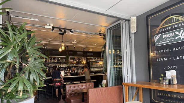 Baaritiskialue, jossa on istumapaikkoja, suuri ruukussa oleva kasvi ja kyltti, jossa on ilmoitettu aukioloajat.