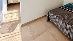 Una habitación con cama, televisión, separador de madera y lámpara colgante.