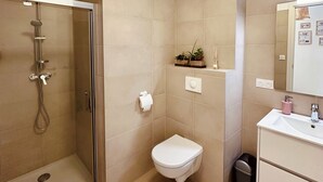 Un baño con cabina de ducha de vidrio, inodoro, lavabo y espejo.