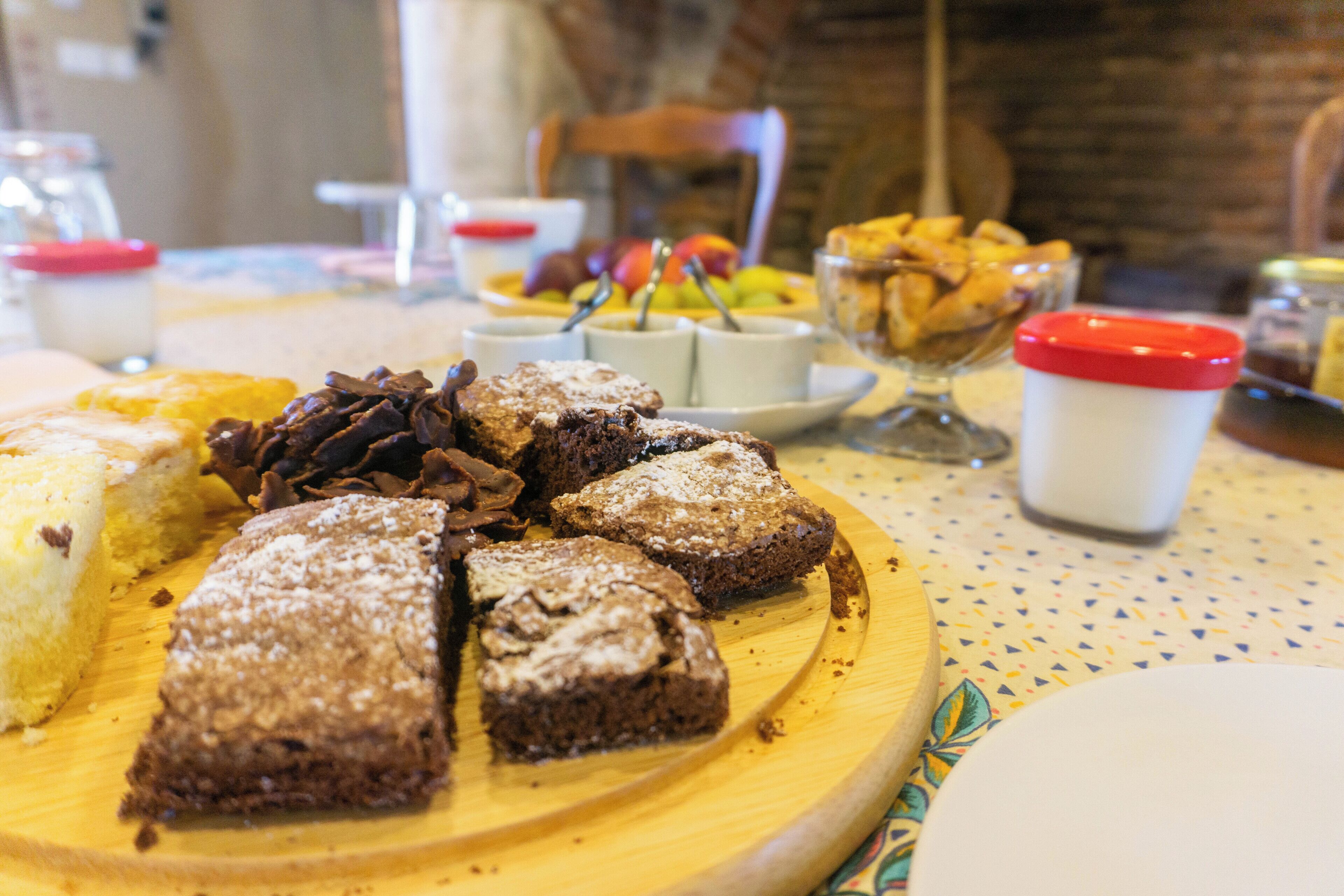 A wooden board with various desserts and a white cup with a red lid.