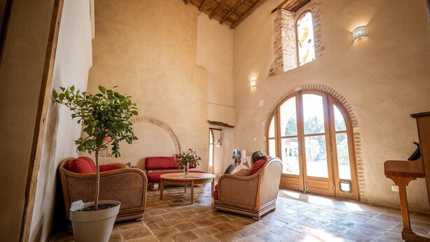 A cozy interior with wicker furniture, a potted plant, and a stone floor. - Les Jardins de la Longagne (Saussenac)