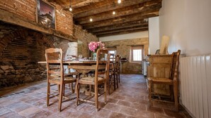 A rustic dining area with wooden furniture, a brick wall, and exposed wooden beams. - Les Jardins de la Longagne (Saussenac)