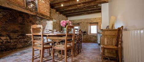 A rustic dining area with wooden furniture, a brick wall, and exposed wooden beams.