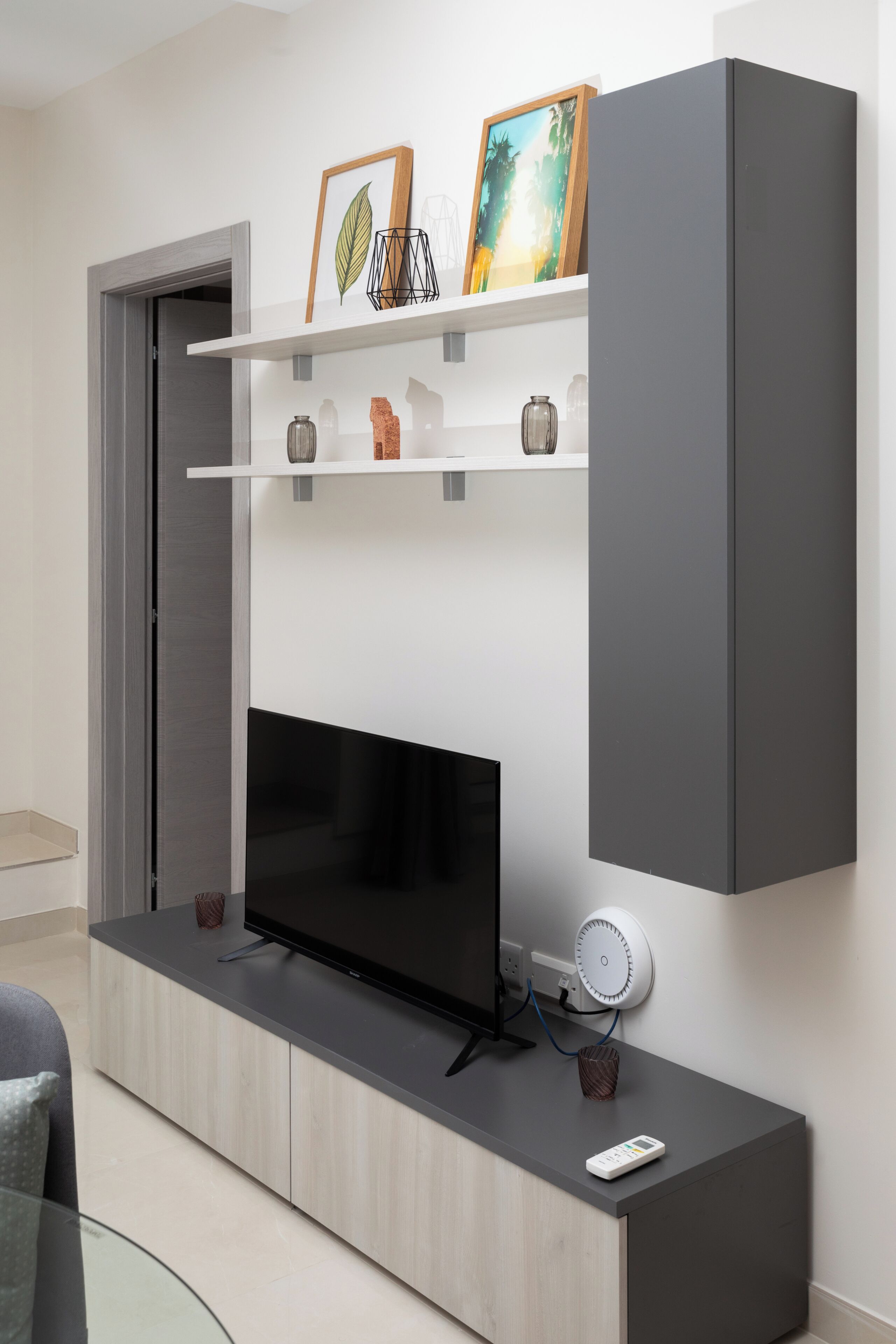 Un salon moderne doté d’un téléviseur à écran plat, d’étagères intégrées et d’un meuble gris.