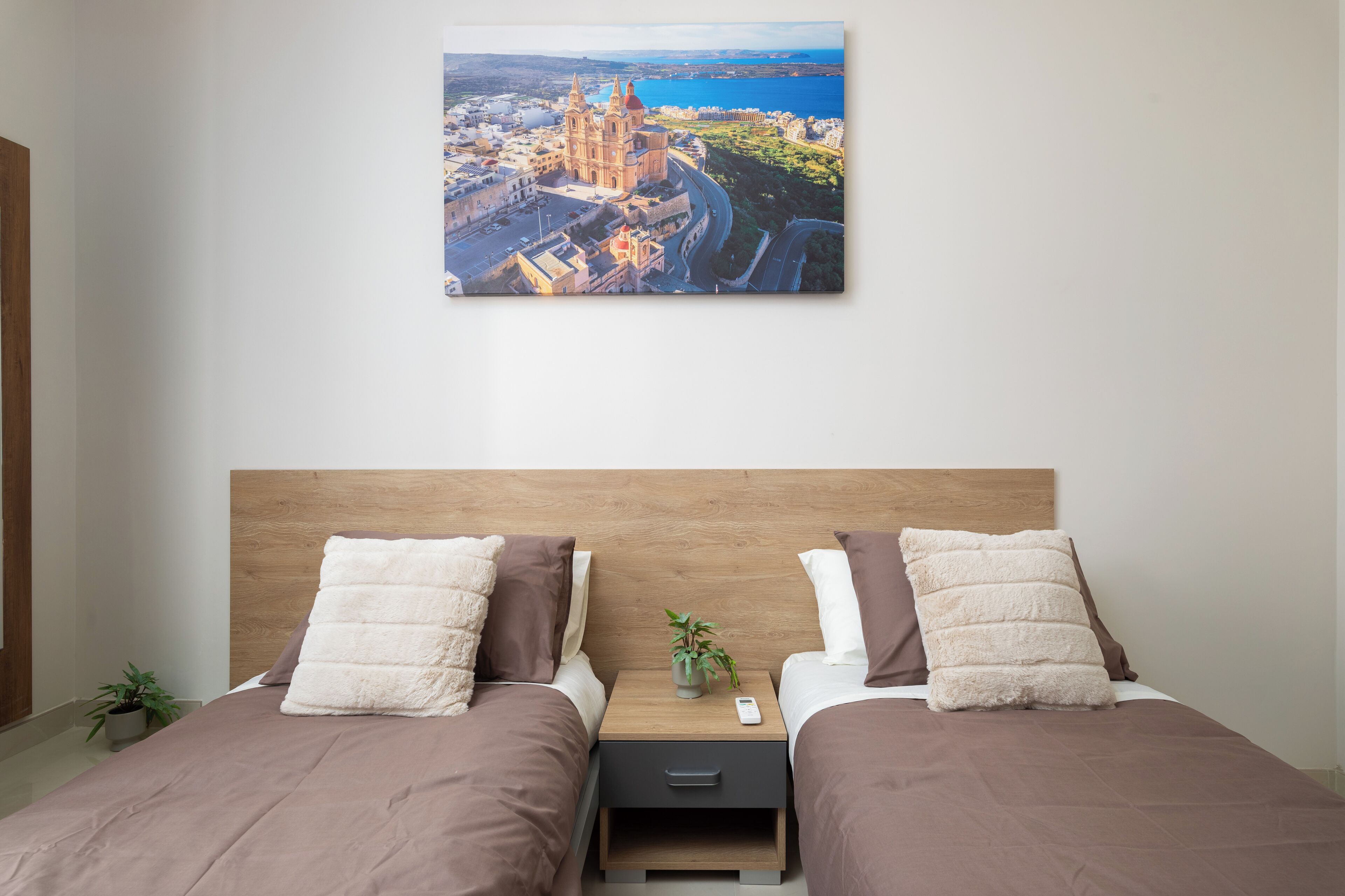 Ein Doppelbett mit Holz Kopfteil, zwei Nachttische, ein Beistelltisch und Blick auf die Stadtlandschaft.