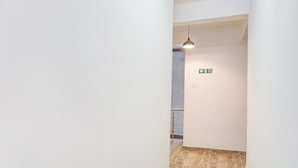 Ein schmaler Flur mit einer Lampe und einem Brandschutztürschild.