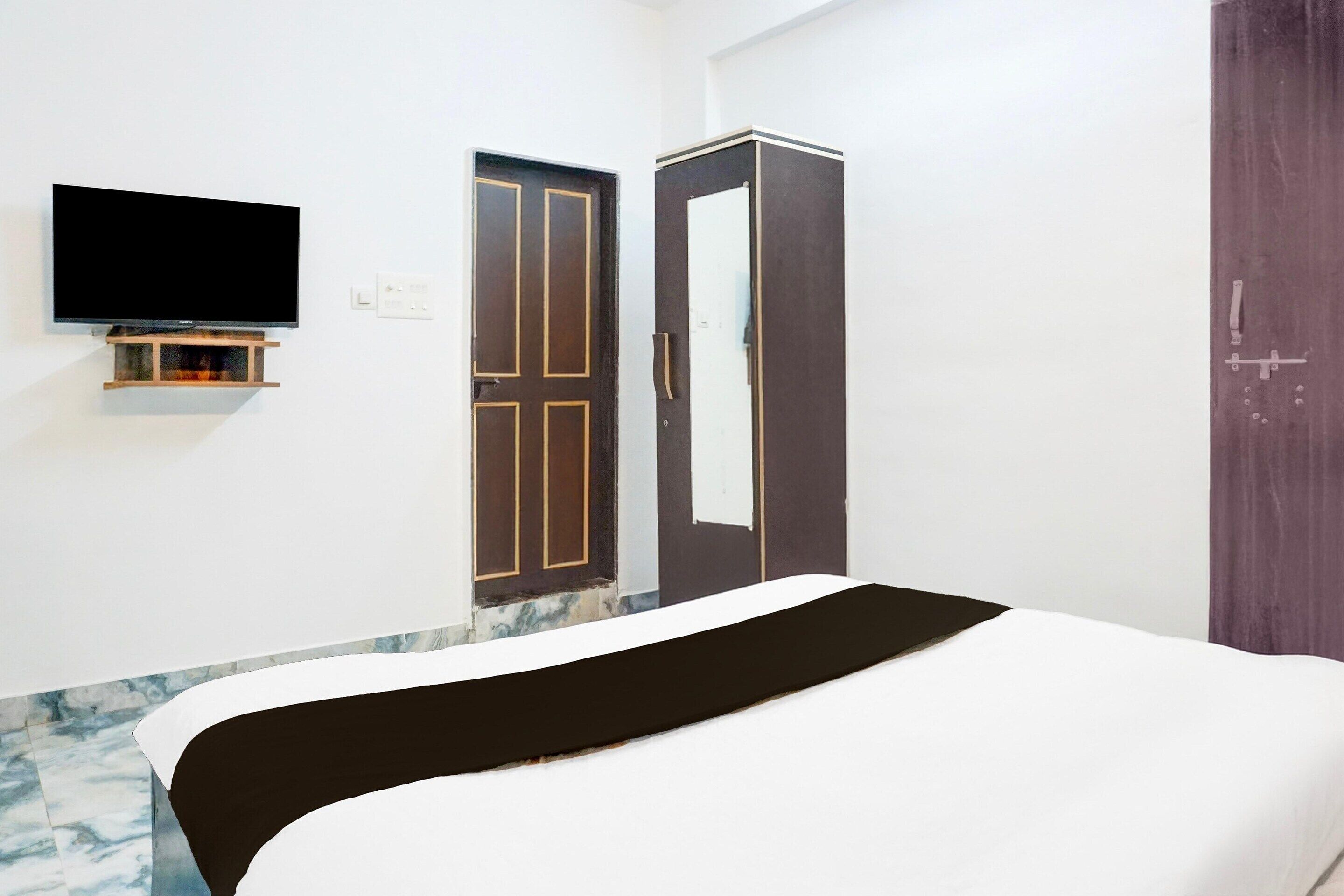 A room with a bed, a wardrobe, a television, and a door.