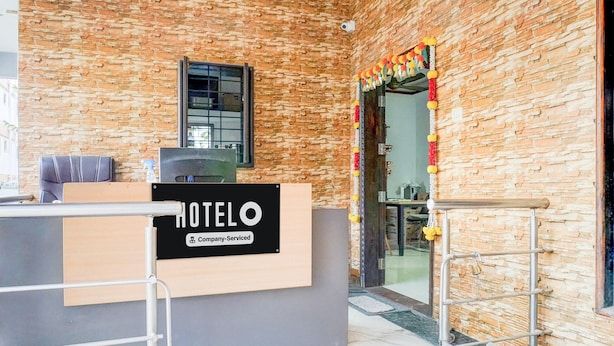 Ein Empfangsschalter mit einem Schild mit der Aufschrift 'HOTEL' und einem firmenzugehörigen Logo. Links befindet sich ein Fenster und rechts eine Tür mit farbenfroher Dekoration.