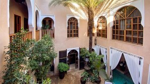 A courtyard with a palm tree, potted plants, and arched windows. - Riad Selouane (Marrakech)