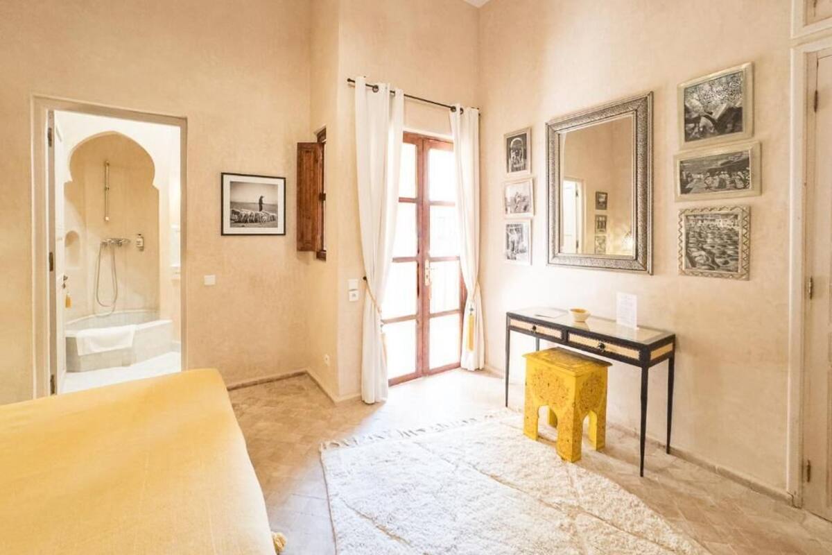 Habitación con ducha, lavamanos, espejo y un taburete pequeño.