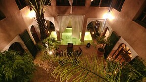 An indoor courtyard with a palm tree, potted plants, and a seating area. - Riad Selouane (Marrakech)