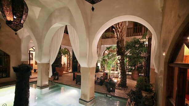 An indoor pool area with arches, seating, and potted plants. - Riad Selouane (Marrakech)